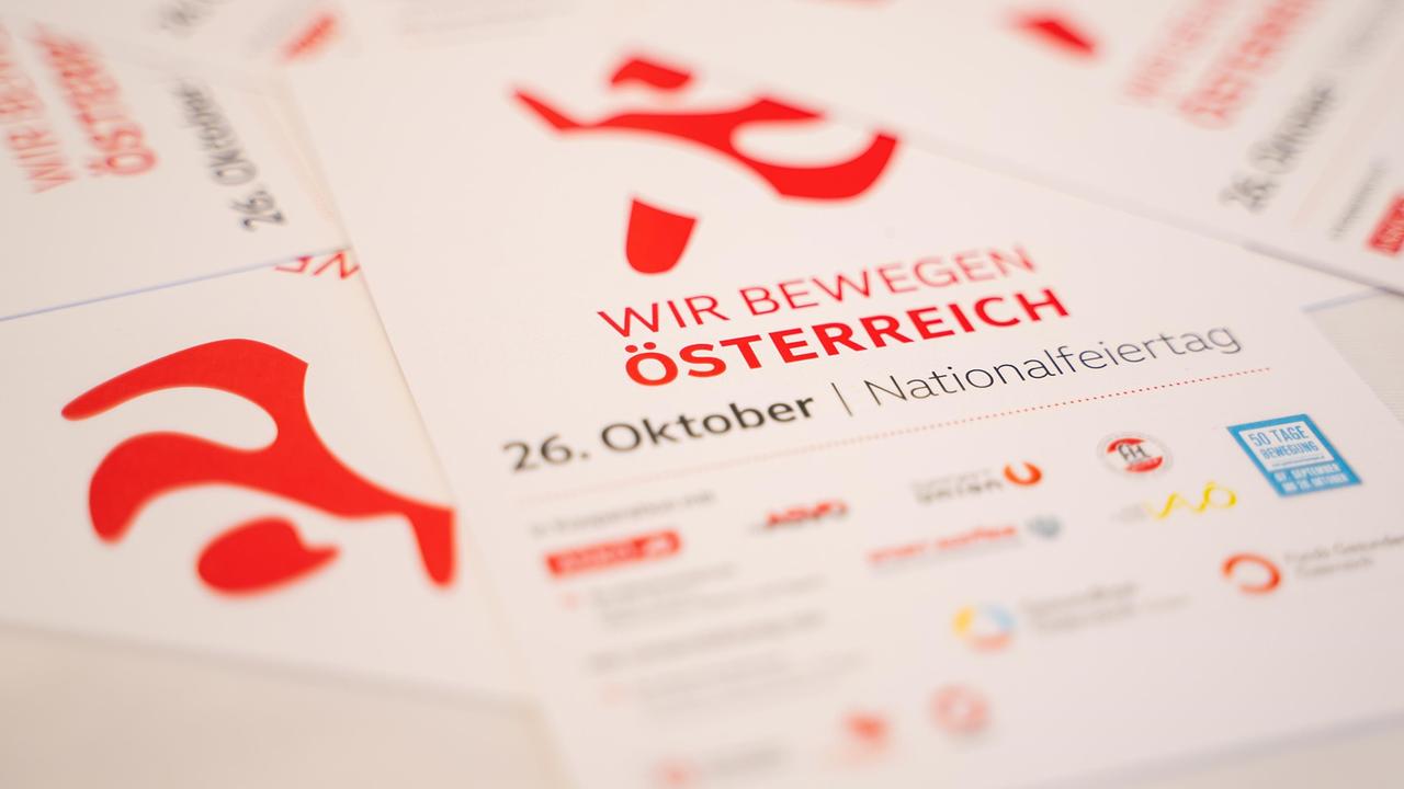 Flyer mit der Aufschrift „Wir bewegen Österreich“ in großen roten Buchstaben, die eine Veranstaltung am 26. Oktober, dem Nationalfeiertag, bewerben. Unten sind unscharf Logos von unterstützenden Organisationen abgebildet.