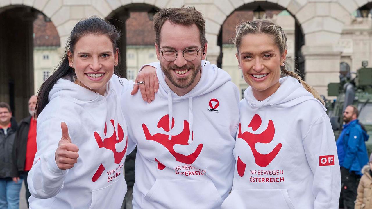 © ORF/Klaus Titzer Conny Kreuter, Andreas Onea und Corinna Kamper strahlen in die Kamera. Alle drei tragen weiße Hoodies mit dem roten WIR BEWEGEN ÖSTERREICH Hoodie.