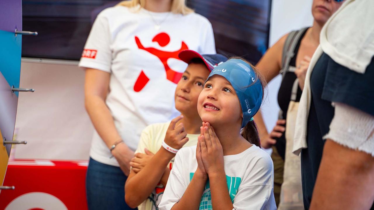 © ORF/Osman Cetin In einem hellen Eventzelt stehen Kinder neugierig vor einem Glücksrad. Rundherum warten weitere Besuchende.
